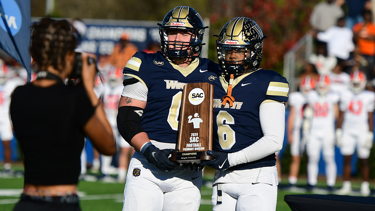 Wingate football players pose with their South Atlantic Conference championship trophy.