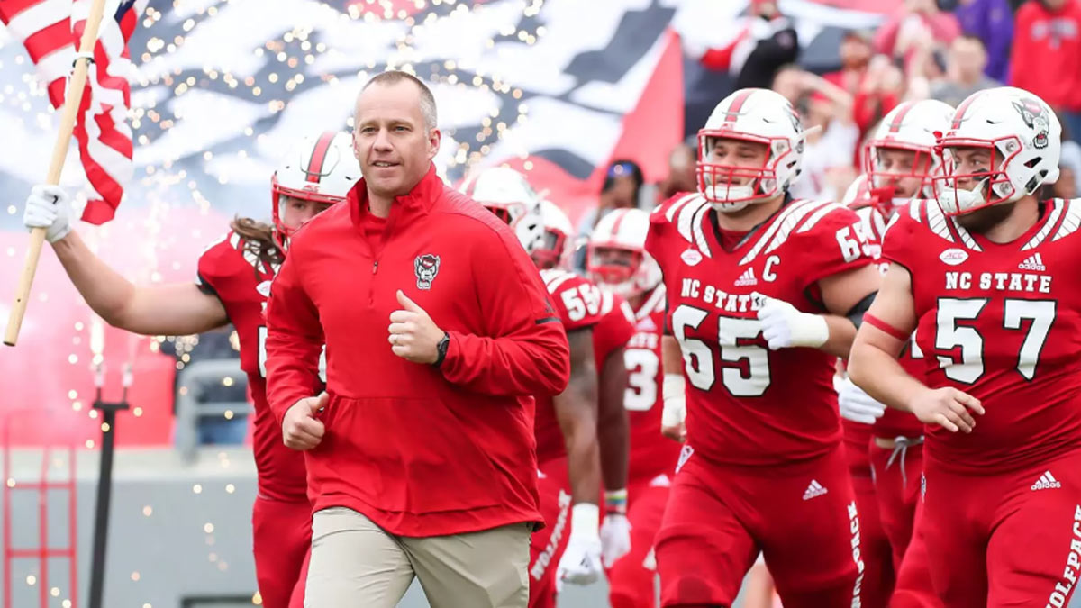 NC State coach Dave Doeren runs onto the field with his players before a game