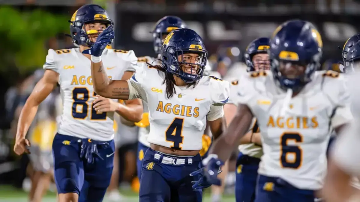 North Carolina A&T football players wear smiles as they run onto the field for a 2025 early season game.