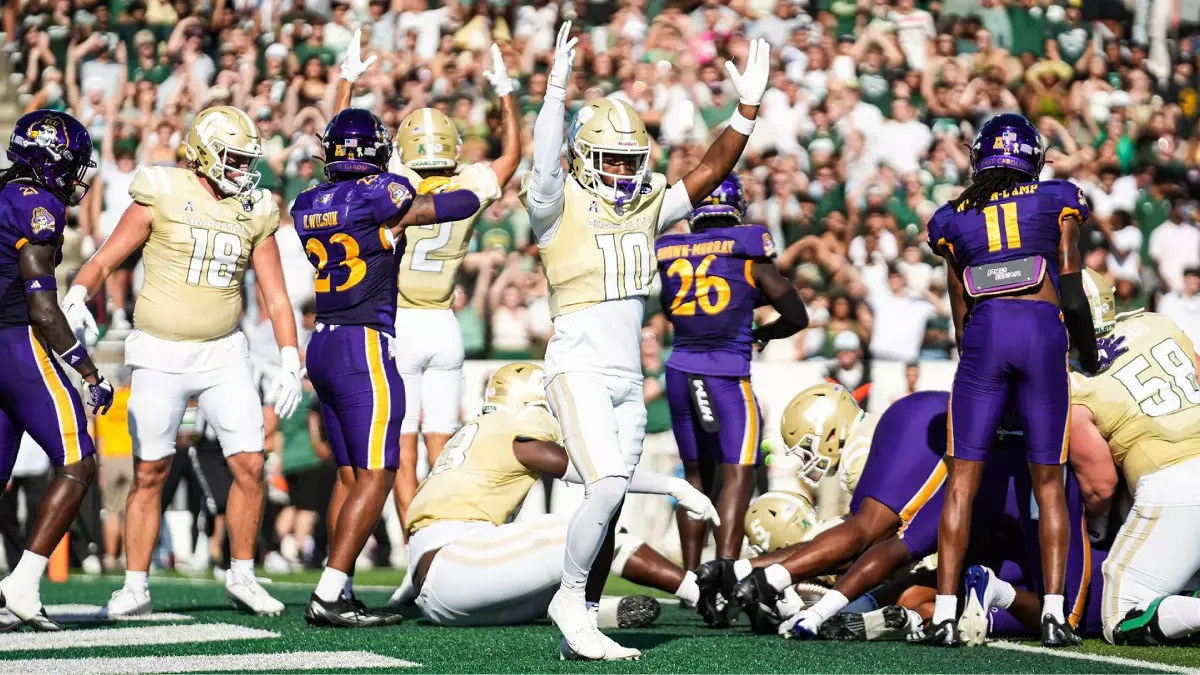 Charlotte football players, clad in all gold uniforms, celebrate a big play against East Carolina during their 2024 showdown.
