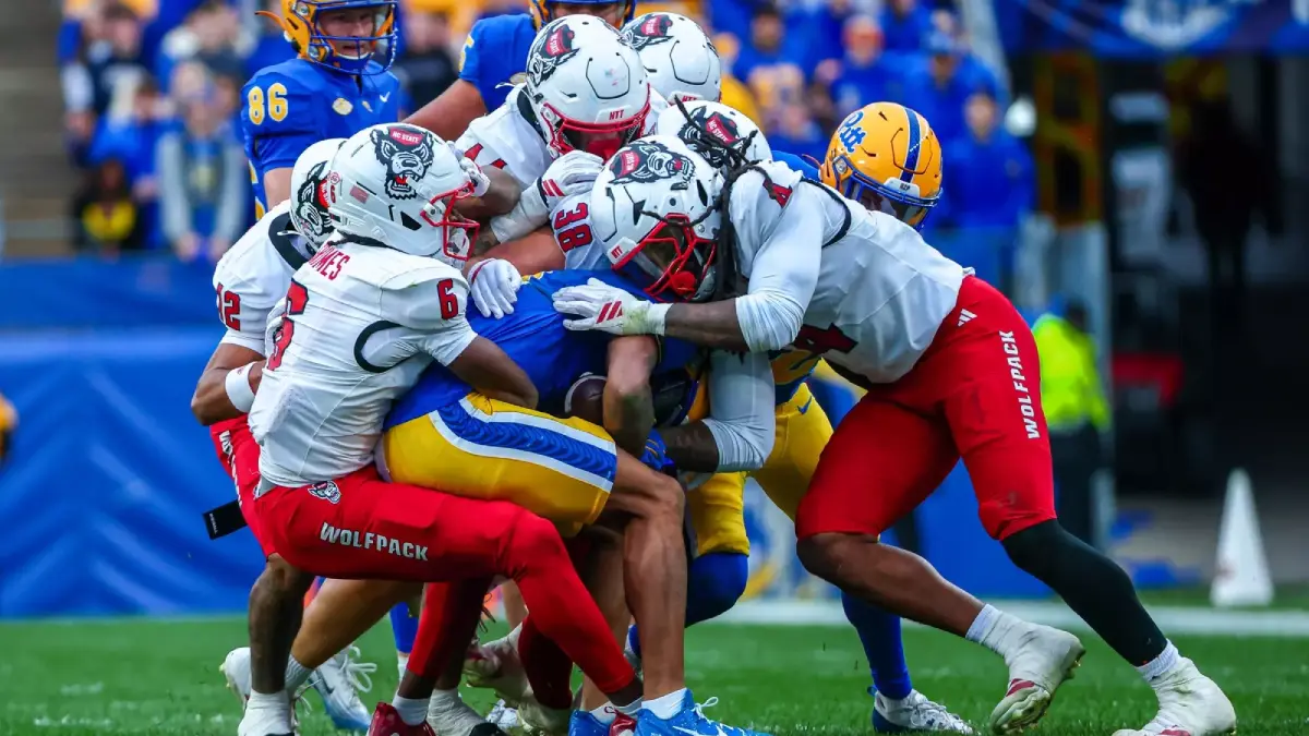 A host of NC State football tacklers surround a Pitt ball-carrier and look to bring him to the ground.