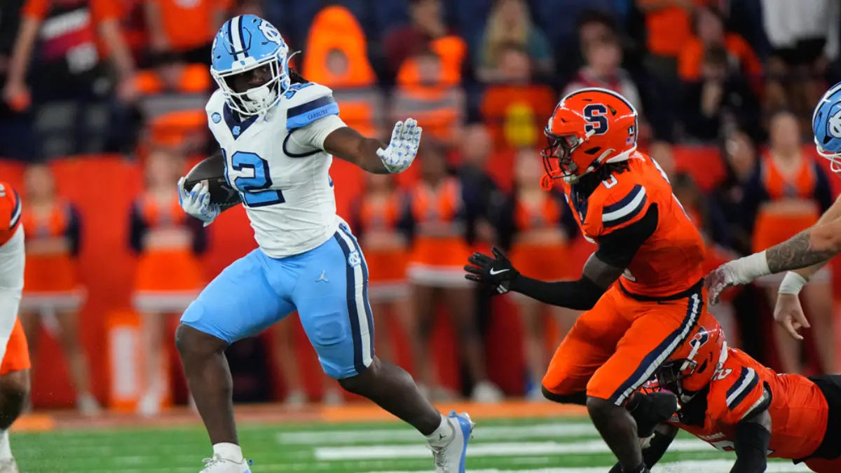 UNC running back Demon June stiff arms a Syrcacuse tackler during a 2025 ACC football game.