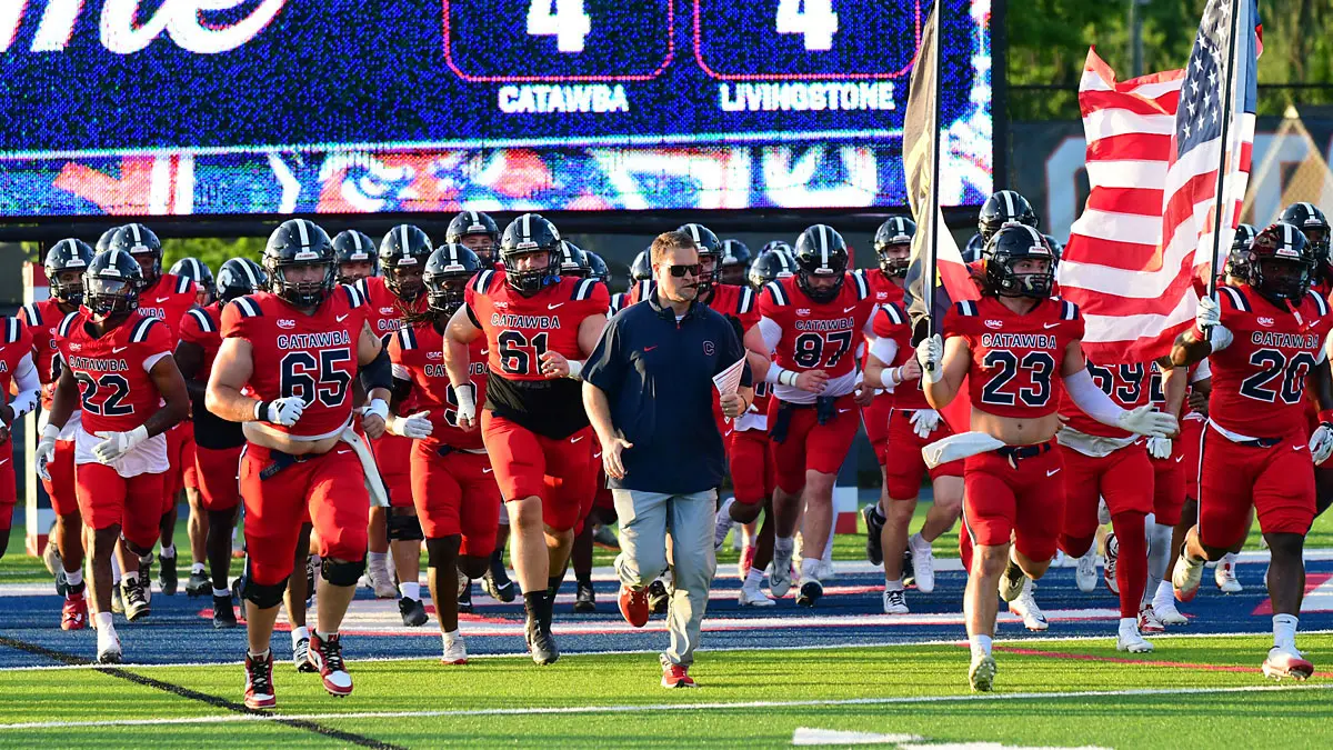 Catawba football players and coach Tyler Haines run out onto the field before the start of a game.