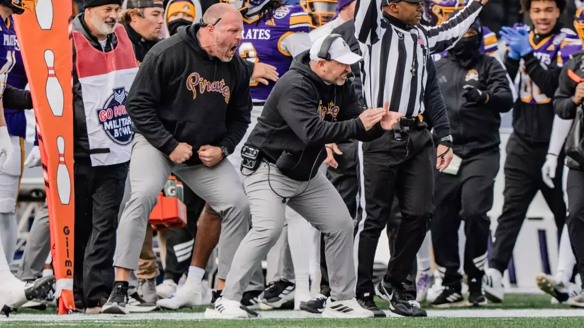 ECU head coach Blake Harrell and the Pirate sidelines cheer on a play.