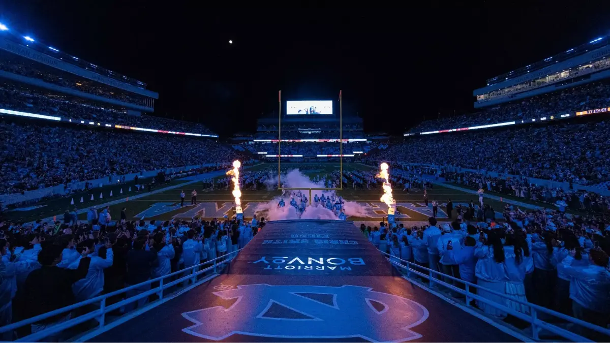 An end zone view of Kenan Stadium in Chapel Hill at night as UNC’s football team runs onto the field.